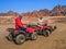Adult man and woman dressed in arafatkas sit on quad bikes