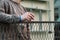 Adult man in working outfit is holding short drink full of vodka and waiting on neighbour. Drinking with friend across fence.