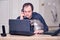 Adult man works with cat from home at a remote location office. Working with a laptop in the kitchen