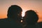 Adult married couple kiss against a sunset.