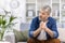 Adult mature man pensive sitting alone at home on sofa close up, gray haired person thinks looks towards window