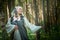 Adult mature woman 40-60 in a green long fairy dress in forest. Photo shoot in style of dryad and queen of nature. Fairy