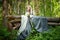 Adult mature woman 40-60 in a green long fairy dress in forest. Photo shoot in style of dryad and queen of nature. Fairy