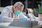 An adult medic wearing glasses and a medical mask records information about patients in his clinic