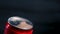 An adult opens a cold aluminum red can of a carbonated drink, beer on a black background. Close up of male fingers