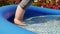 Adult paddles in inflatable paddling family pool in garden