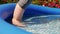 Adult paddles in inflatable paddling family pool in garden