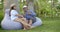 Adult pair of spouses are sitting on beanbag chairs, holding wineglasses, man is taking selfie with wife