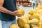 Adult person selecting fresh melon in supermarket. Man holding a big yellow melon in his hands