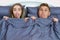 Adult positive couple in bed under the covers showing tongue and looking at the camera