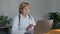 An adult professional female doctor communicates by video call using a laptop