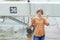 An adult red-haired woman with a serious face stands with crossed fingers in front of a boarding bridge on a plane at the airport