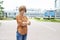 An adult redhead woman in casual clothes stands in the street with her arms crossed in annoyance