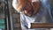 Adult repairman in protective eyewear examining a fixed pipe on table at workshop. Male mechanic preparing to weld metal