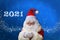 Adult santa claus with white beard on a beautiful blue background blows snow from the palm, christmas concept, waiting for gifts,