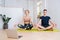 Adult siblings doing yoga together during isolation home, sitting in easy pose