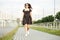 Adult smiling girl is walking down the street in a summer dress. The concept of the style of life, urban and active life