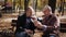 Adult son of an elderly father teaches the smartphone in autumn Park on a bench.