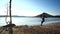 Adult sprinter in red jersey and black tights running quickly along coastline of island within morning