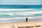 Adult surfer in wetsuit carrying surfboard on a sandy beach