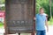 An adult tall man turns a metal drum in a Buddhist temple with his head