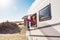Adult tourist woman opening camper van window to enjoy the sun and freedom. Concept of travel people for summer holiday vacation