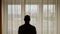 Adult white caucasian sports men standing in front of window with raised hands at sunrise. Men silhouette. He feels free