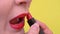 Adult woman applies bright red lipstick. shooting of mouth on yellow background