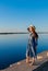 Adult woman in blue dress and straw hat walking near the river. Fortieth people