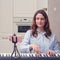 An adult woman in a blue nightgown looks at the phone on a tripod plays music on the home piano