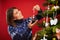 Adult woman decorating Christmas tree over red background