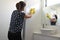 Adult woman with face mask and working rubber gloves cleaning and sanitizing home bathroom using disinfectant bleach cleaner to