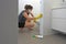 Adult woman with face mask and working rubber gloves cleaning and sanitizing home rest room using disinfectant bleach cleaner to