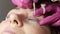 Adult woman face on modern eyelash lamination procedure in a professional beauty salon. The master applies special glue
