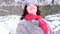 An adult woman in a fur coat and hat, with a red scarf, turns around, rejoicing in the snow and gives a kiss in slow motion