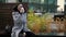 adult woman in grey coat is drinking coffee from carton cup in downtown