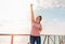 An adult woman happily raises her hand up. In the background, the sky with clouds, Sunny weather. Copy space. Concept of human