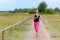 Adult woman jogging towards camera along road