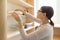 Adult woman picking food from storage cabinet in kitchen, storage with wooden shelves