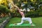 Adult woman practice yoga outdoor in garden on grass summer day