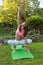 Adult woman practice yoga outdoor in garden on grass summer day