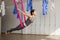 Adult woman practices inversion anti-gravity yoga position in gym.