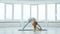 Adult woman practicing revolved wide-legged forward fold pose in yoga studio