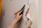 Adult woman removes old wallpaper from the walls. Hands with a r