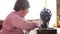 Adult woman sews on the old manual sewing machine. Glasses are dressed and gray cloth is sewn on.