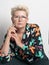 Adult woman with short hair, blonde. with glasses posing at the camera. There is a light background in the studio. Close-up