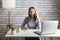 Adult woman sit at desk in living room study on laptop making notes, happy young woman work on computer.