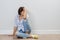 Adult woman sitting near the wall on floor holding her head with hands, covered face. Problems, stress, headache, depression,