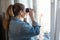 Adult woman spying out the window looking through binoculars, a domestic room