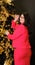 Adult woman in stylish red suit decorates christmas tree